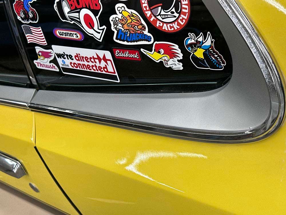 A yellow car with a lot of stickers on it