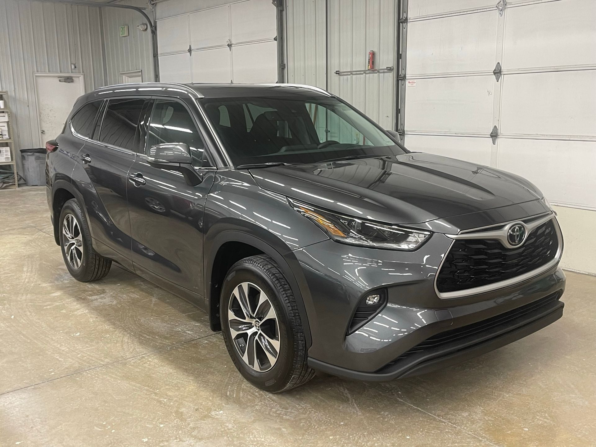 A gray toyota highlander is parked in a garage.