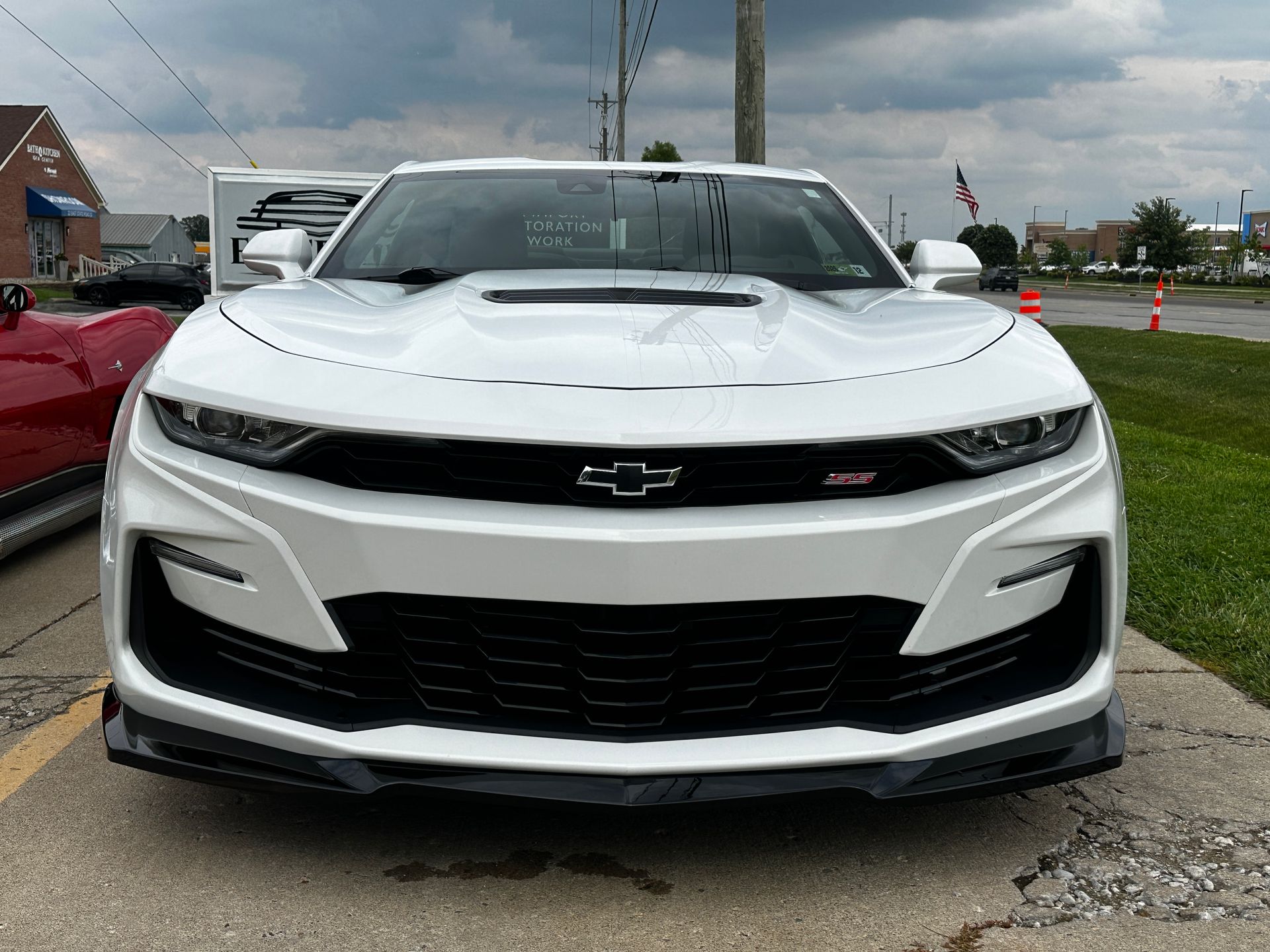 White Chevrolet Camaro sports car with black accents, parked outside on a cloudy day.