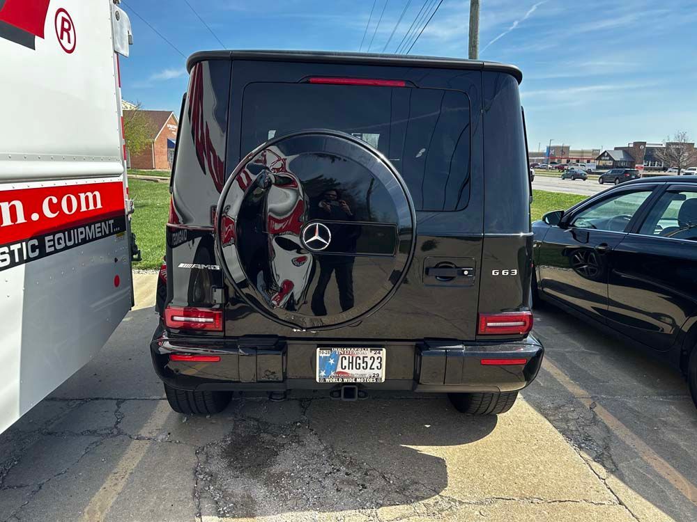 A black mercedes benz is parked in a parking lot