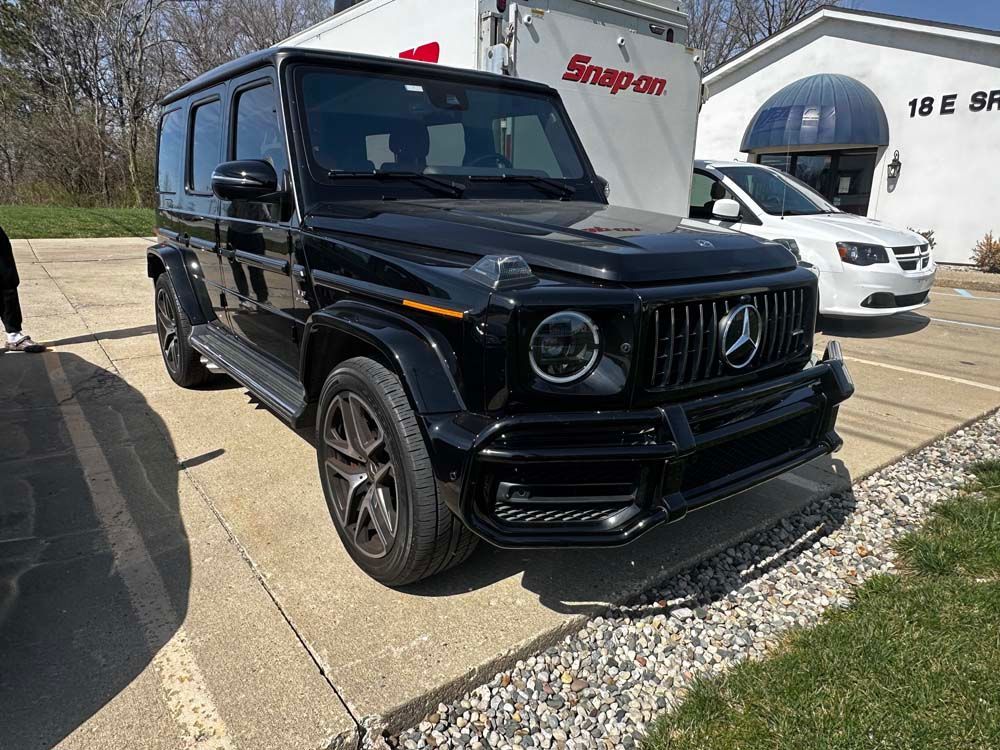 A black mercedes benz g63 amg is parked in a parking lot.