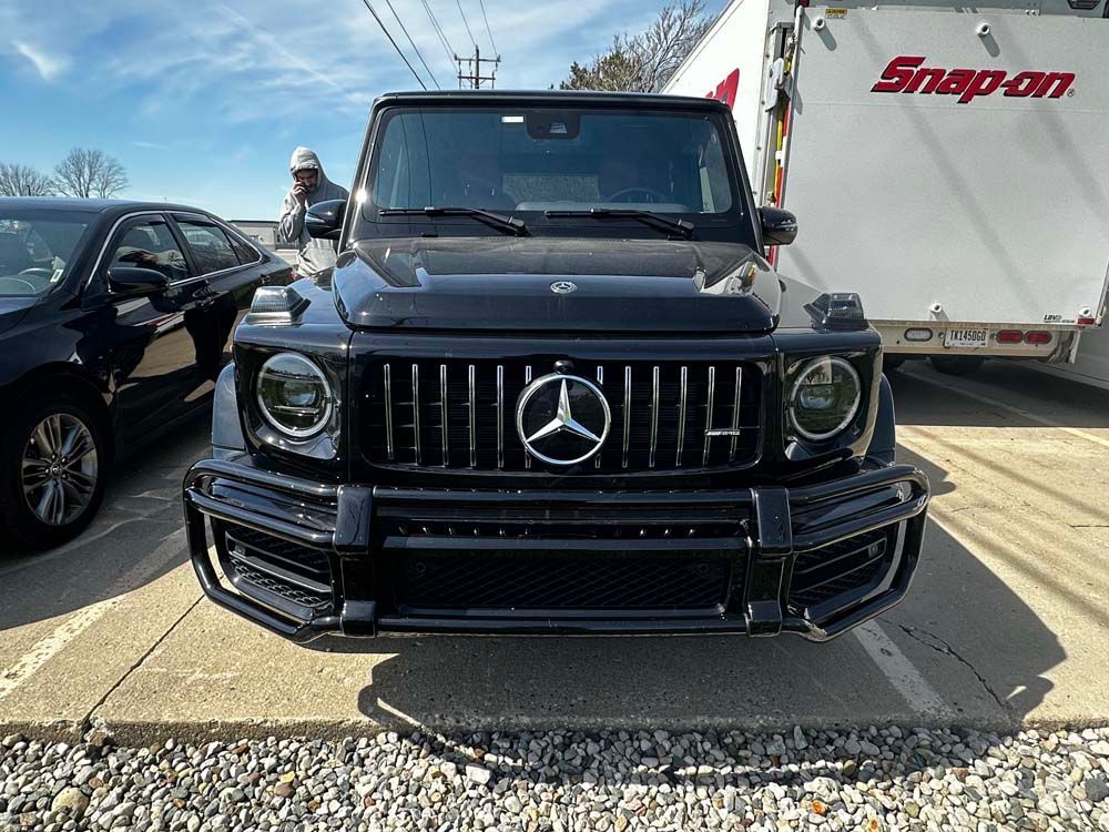 A black mercedes benz g63 amg is parked in front of a snap on trailer.
