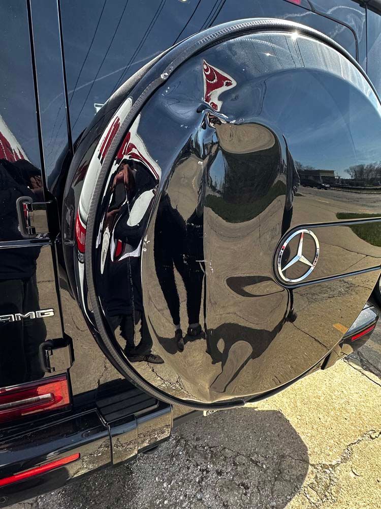 A close up of a mercedes wheel cover with a reflection of a person in it.