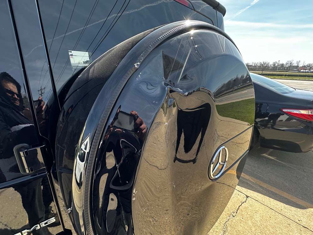 A person is taking a picture of the back of a black car.