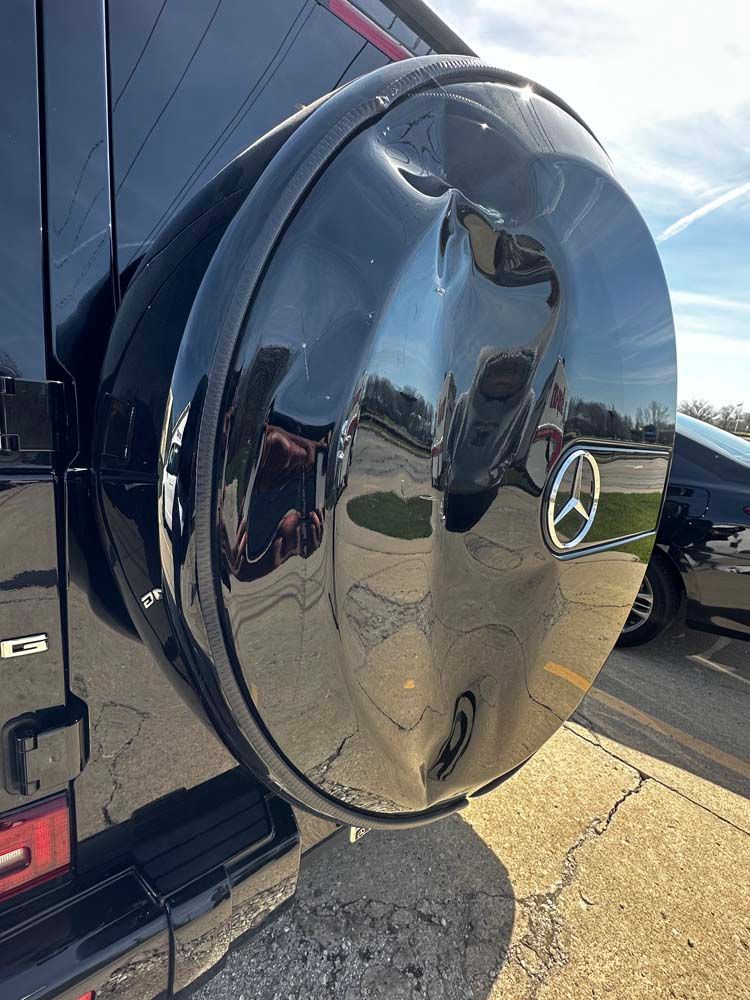 A close up of a tire cover on a black mercedes benz g63.