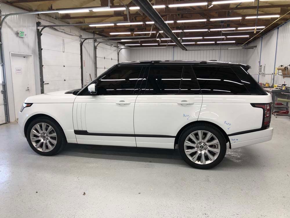 A white range rover is parked in a garage.