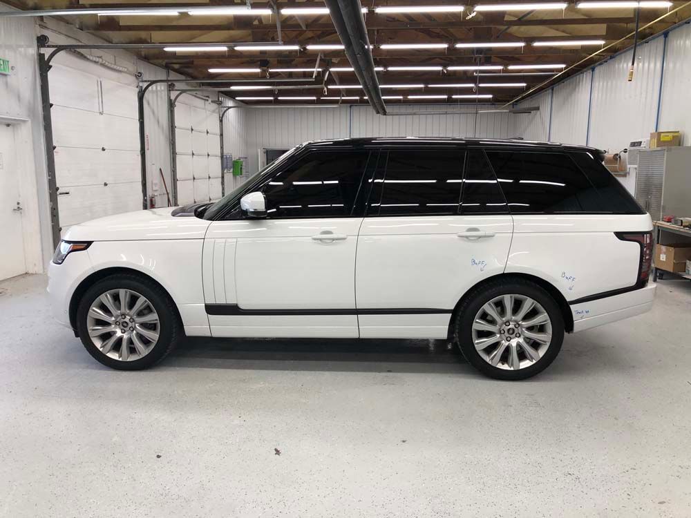 A white range rover is parked in a garage.