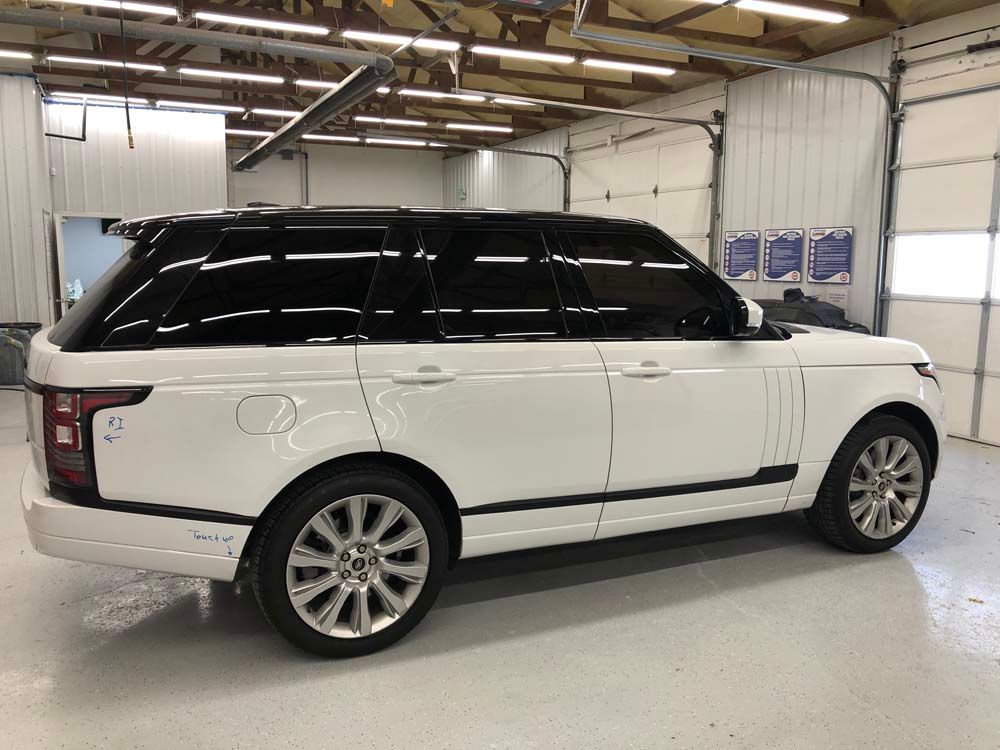 A white range rover is parked in a garage.