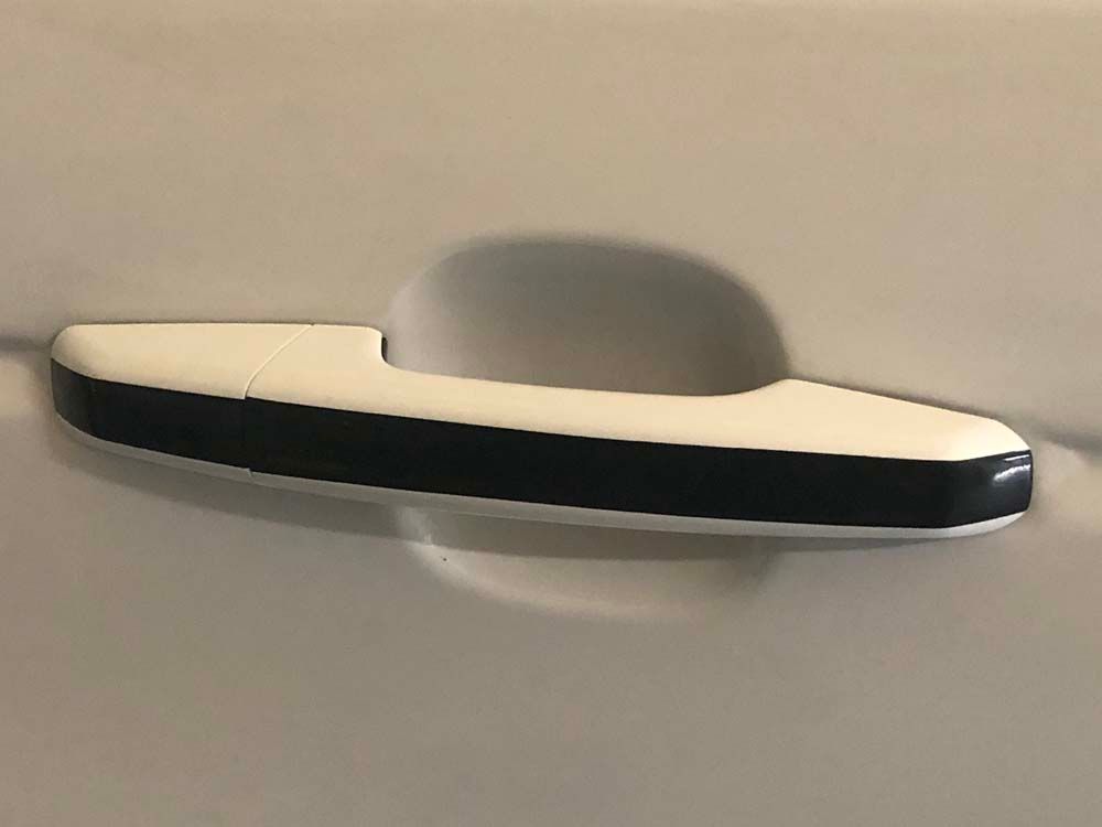 A close up of a white door handle with a black stripe on it.