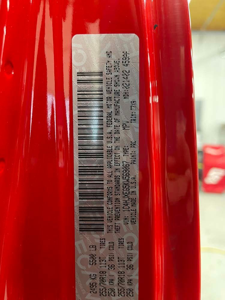 A close up of a red car with a barcode on it.