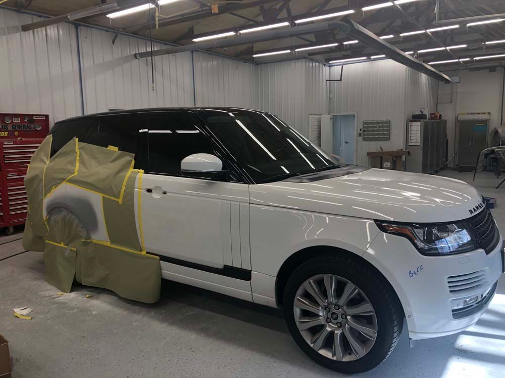 A white range rover is being painted in a garage.