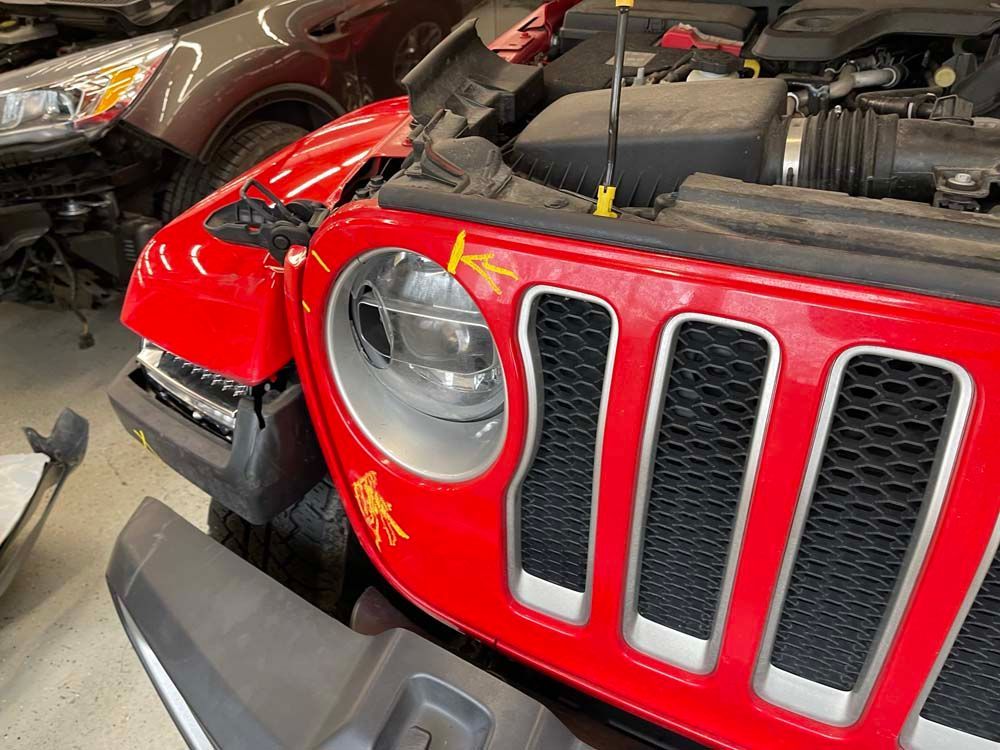 A red jeep is being repaired in a garage.