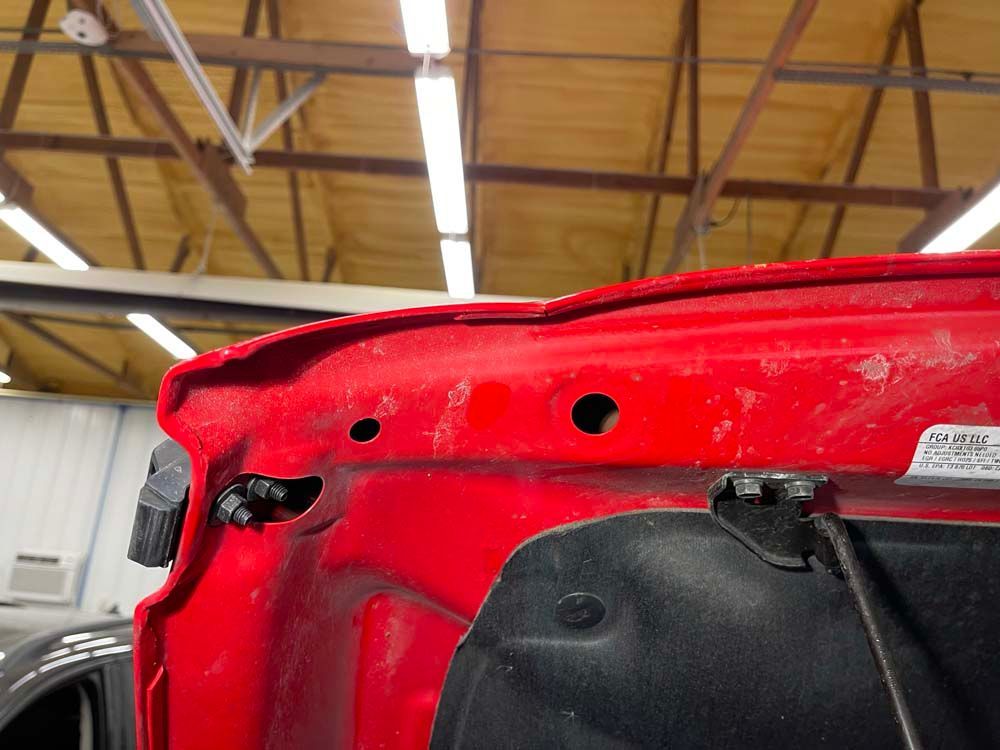A close up of a red car hood in a garage