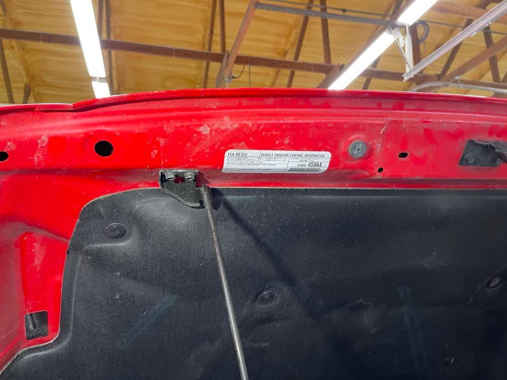 The hood of a red ram truck is open in a garage.