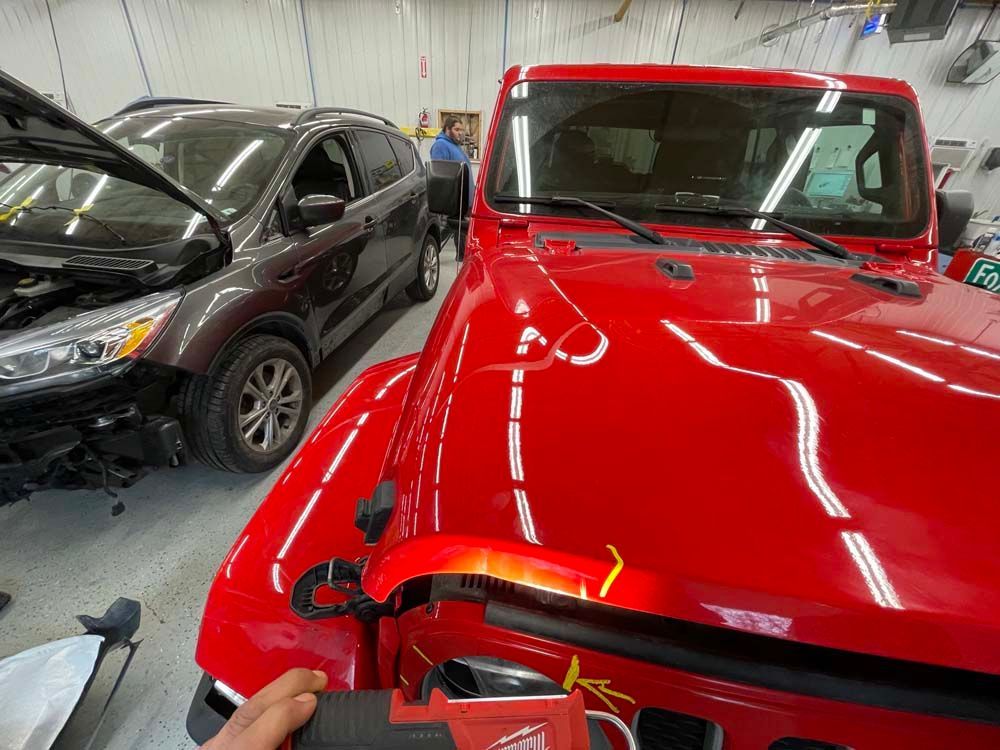 A red jeep is being worked on in a garage.