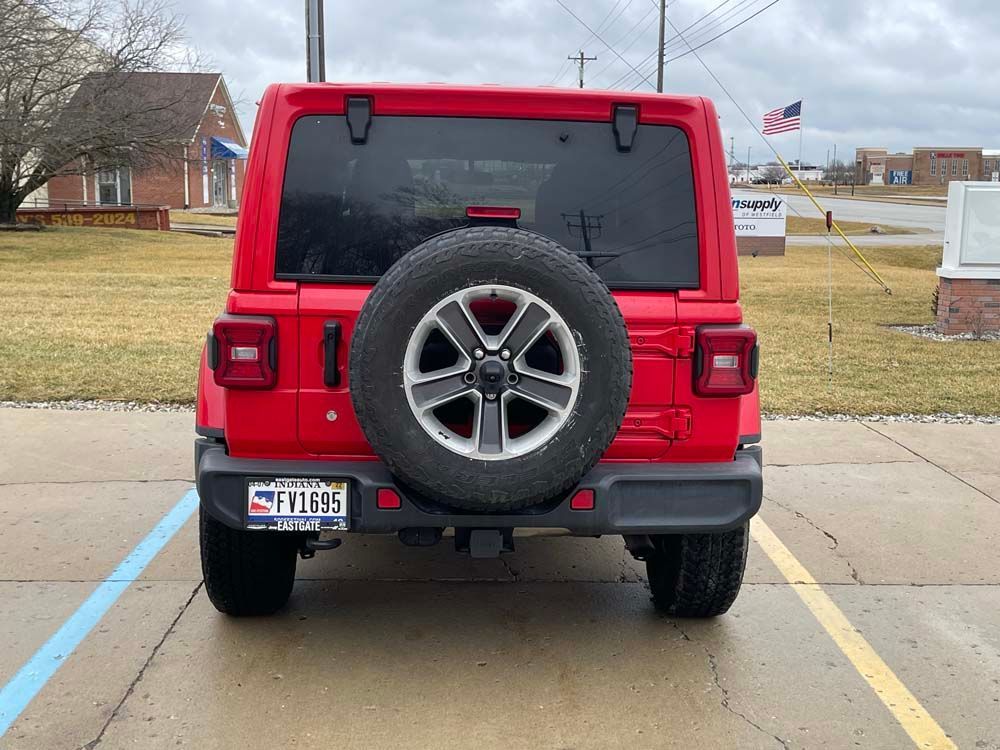 A red jeep with a spare tire is parked in a parking lot.