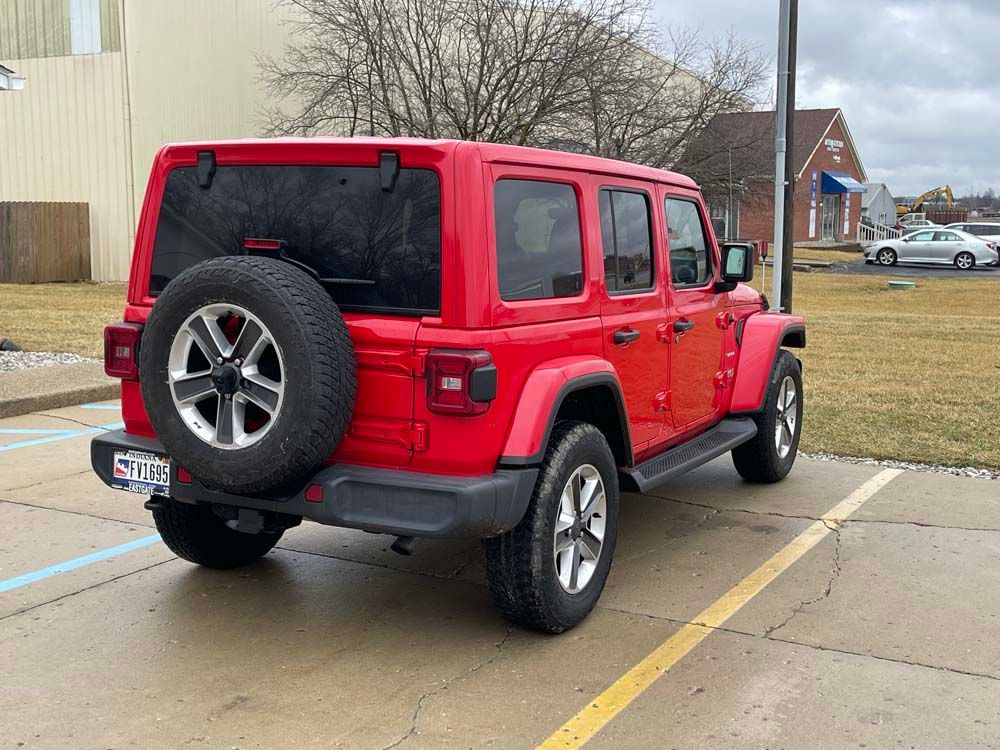 A red jeep wrangler is parked in a parking lot.