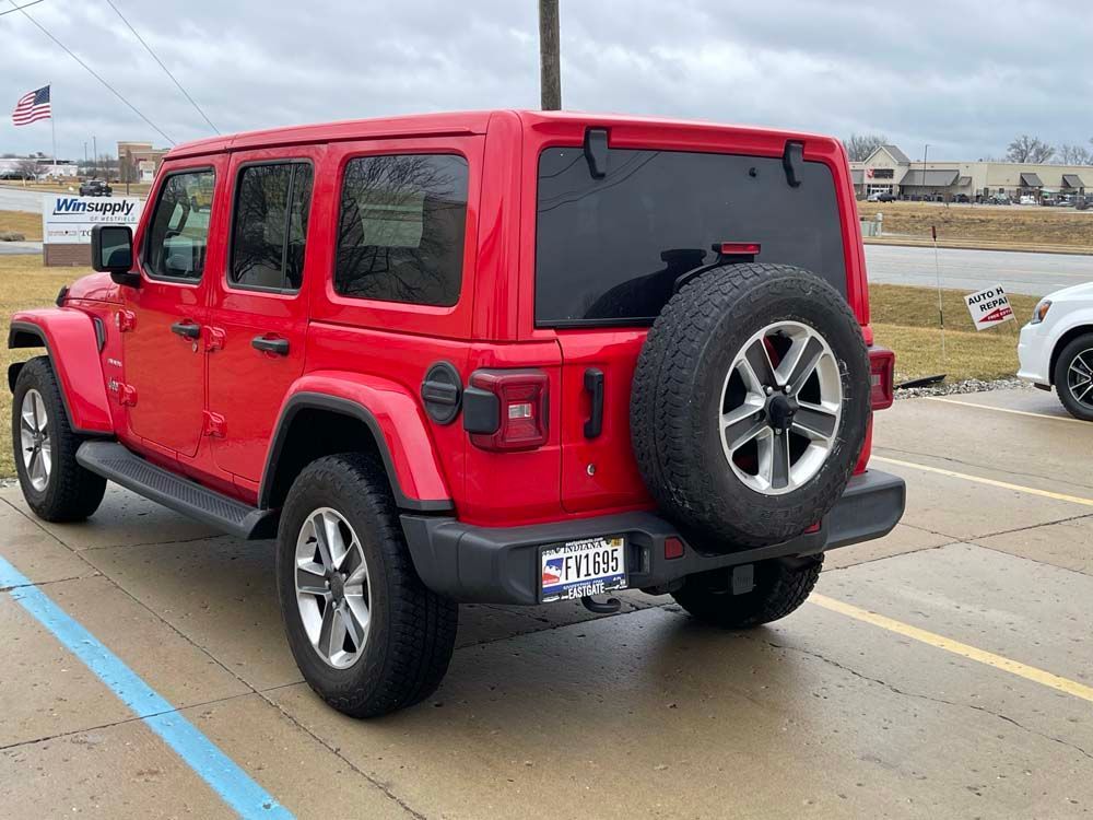 A red jeep wrangler is parked in a parking lot.
