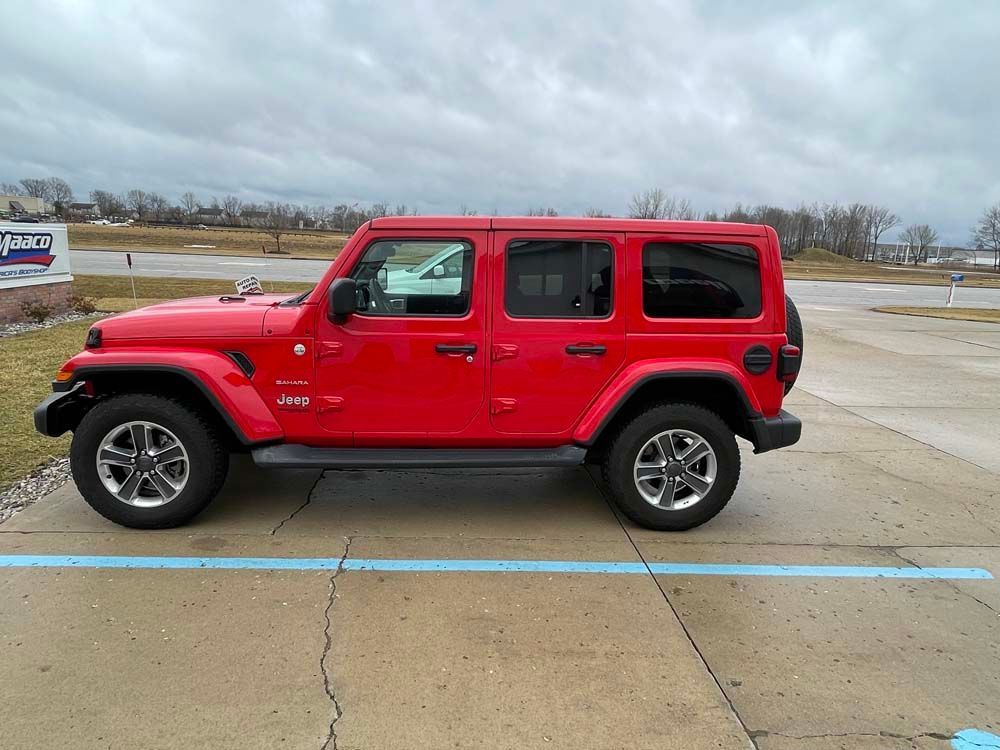 A red jeep wrangler is parked in a parking lot.