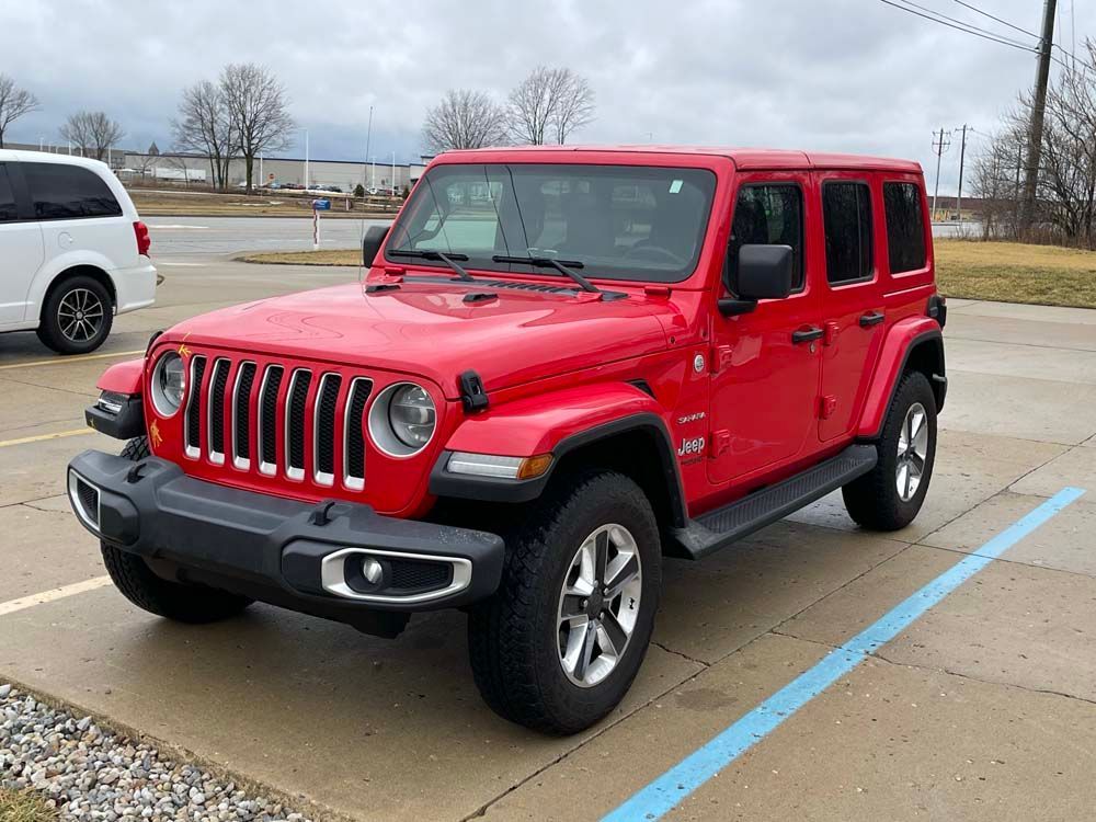 A red jeep wrangler is parked in a parking lot.