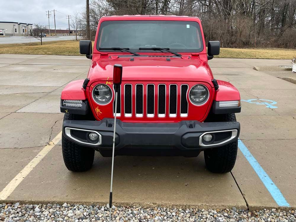 A red jeep is parked in a handicapped parking spot