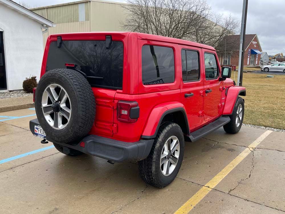 A red jeep wrangler is parked in a parking lot.