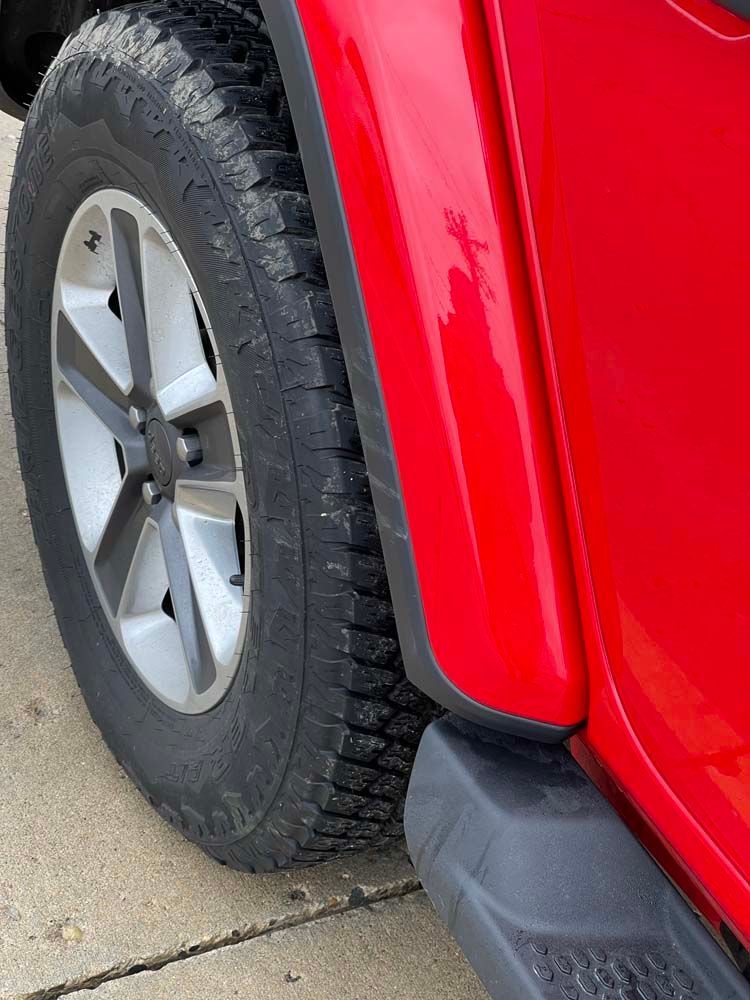 A red jeep is parked on the side of the road.