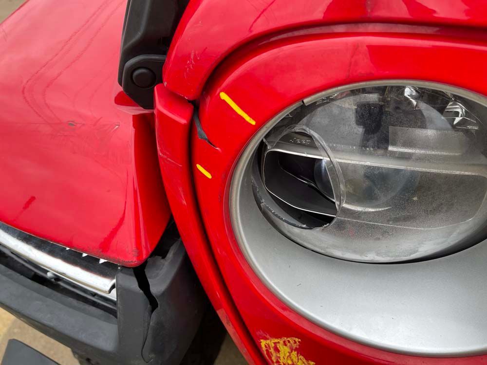 A close up of a red car 's headlight and hood