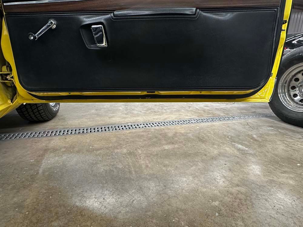 A yellow car is parked in a garage with the door open.