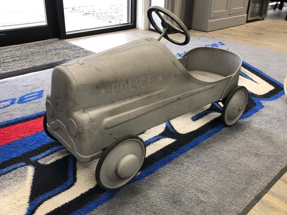 An old pedal car is sitting on a rug in a room.