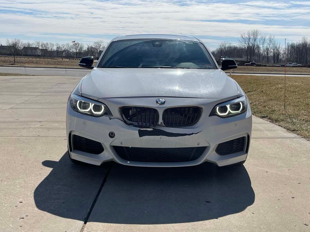 A white bmw is parked in a driveway on a sunny day.
