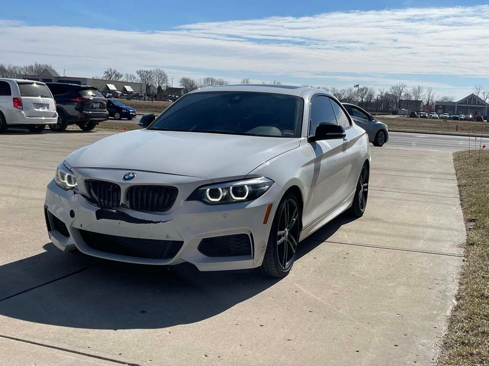 A white bmw 2 series coupe is parked in a parking lot.