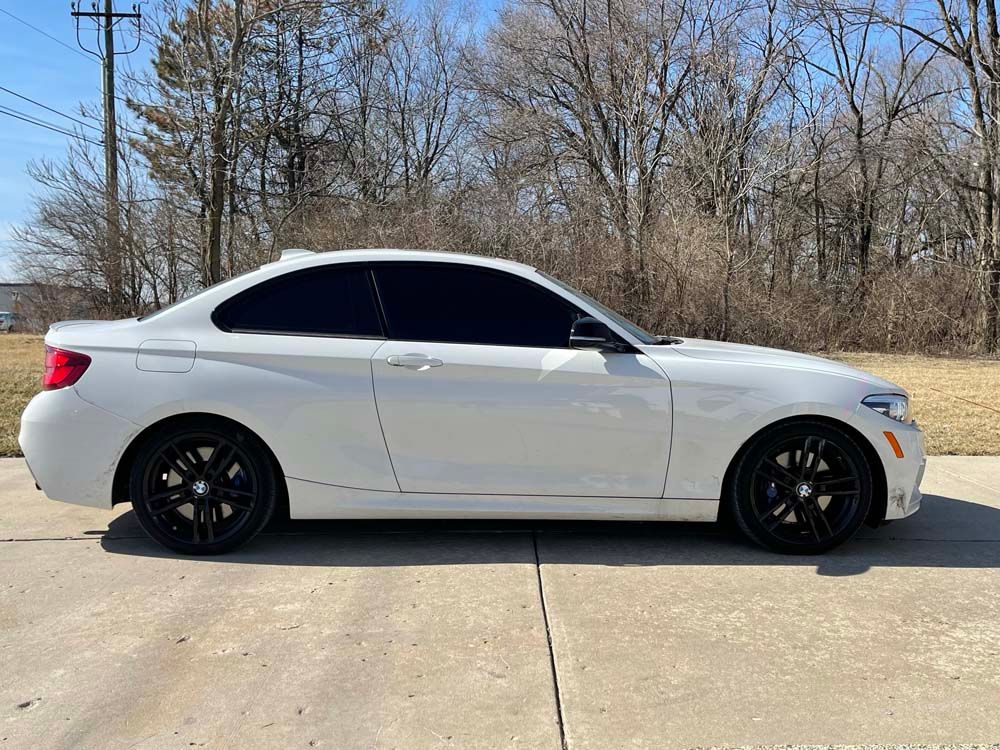 A white bmw is parked on the side of the road.