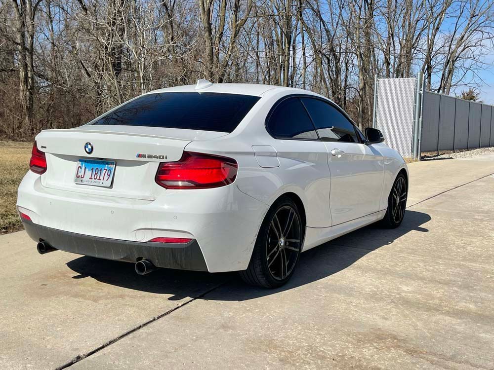 A white bmw is parked on the side of the road.