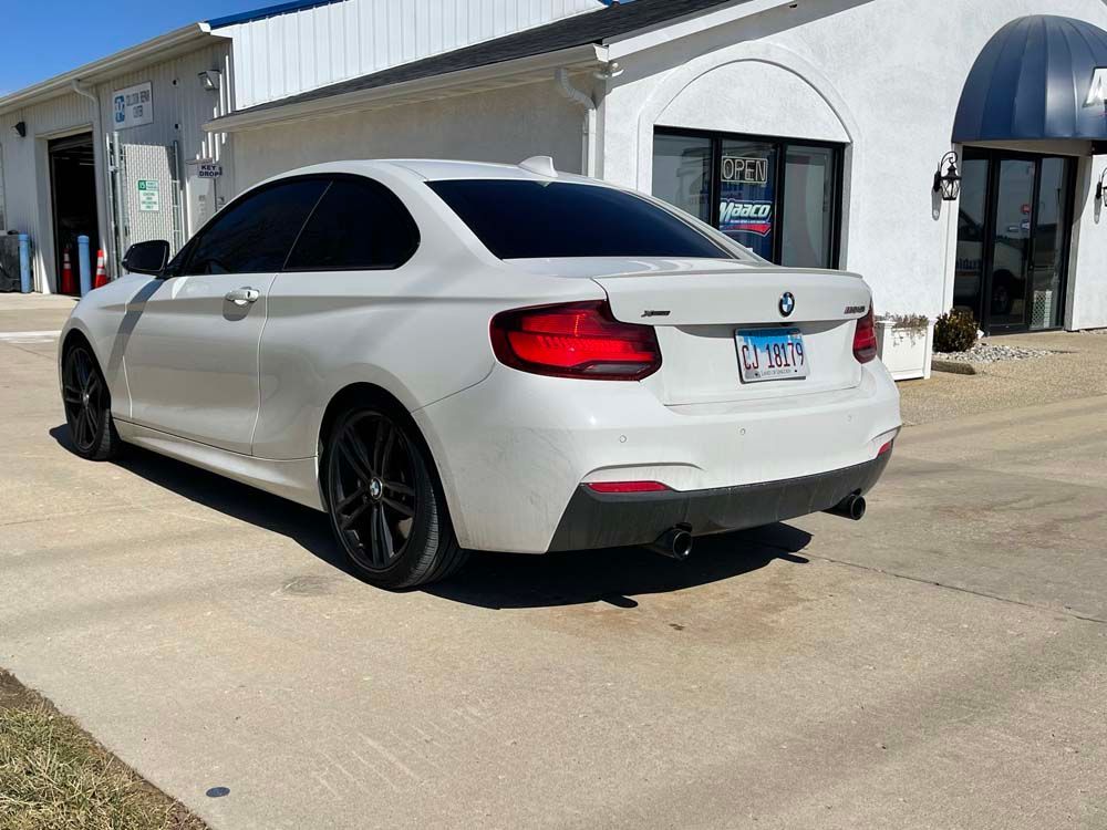 A white bmw is parked in front of a white building.