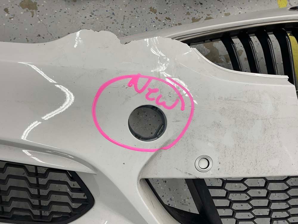 A white car bumper with a pink circle around it that says new