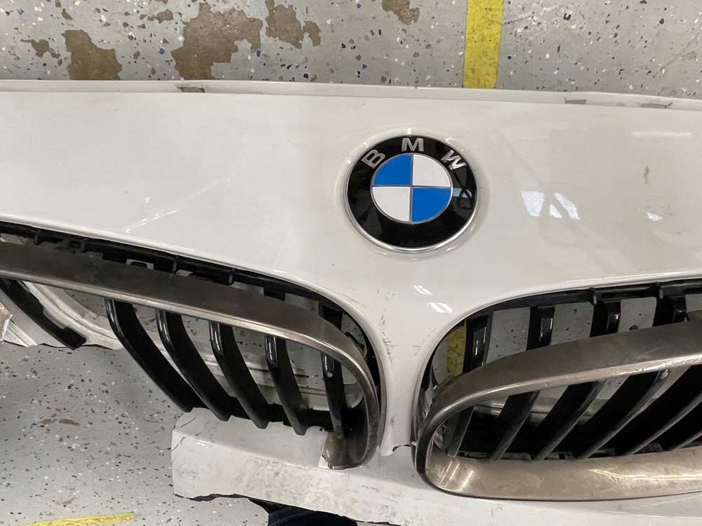 White BMW front bumper with black grille and logo.
