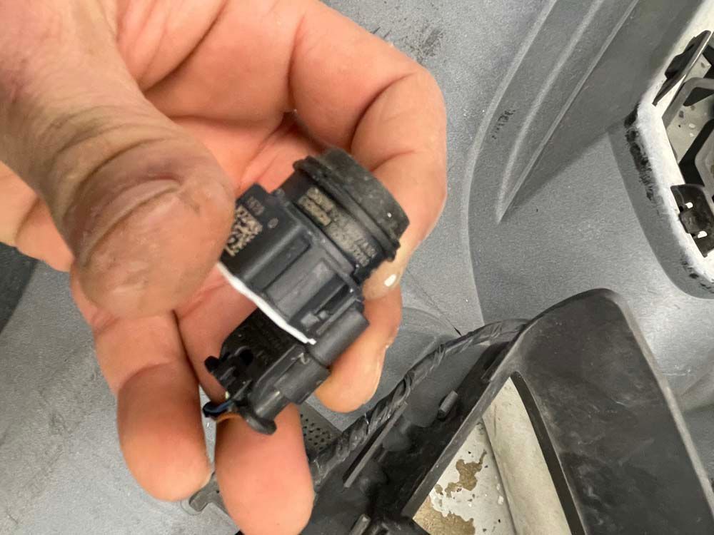 A person is holding a small black object with bosch written on it