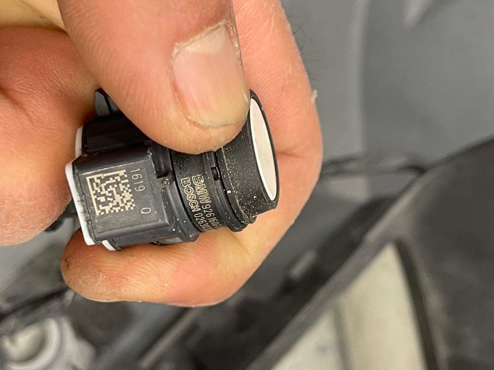 A person is holding a small black object in their hand.