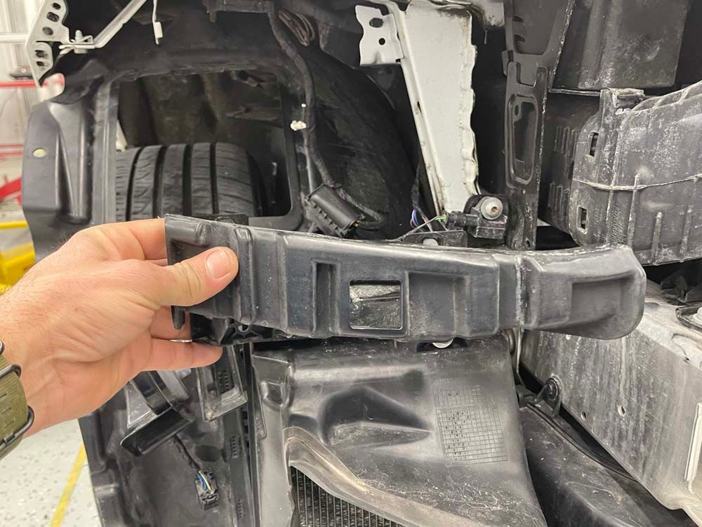 A person is holding a piece of plastic on the side of a car.