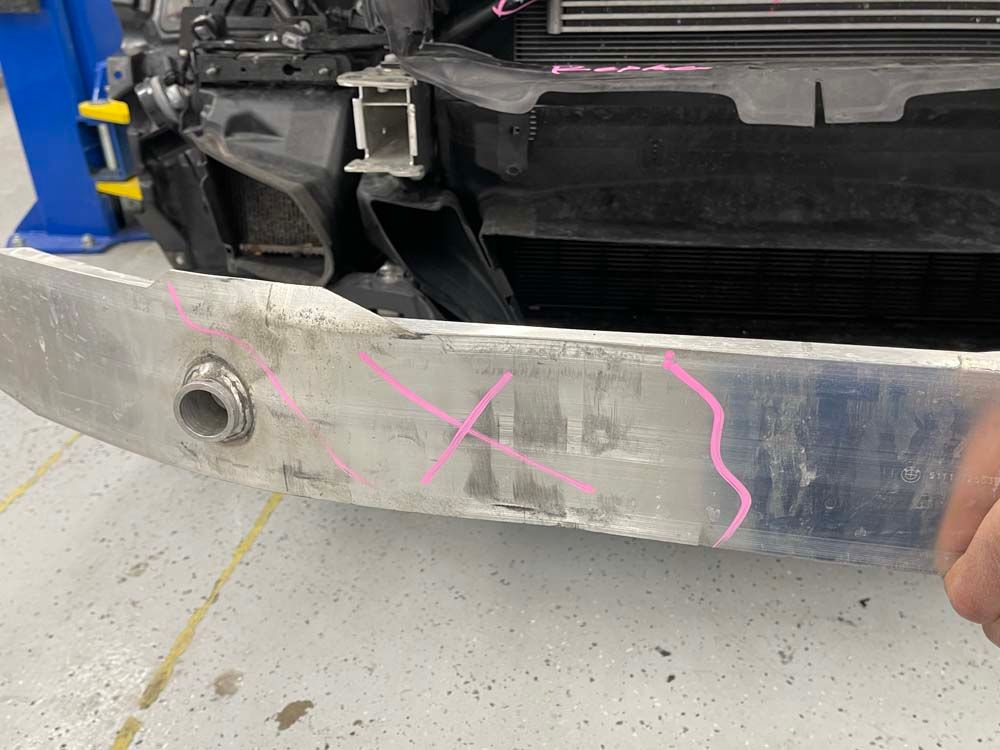 A person is holding the front bumper of a car in a garage.