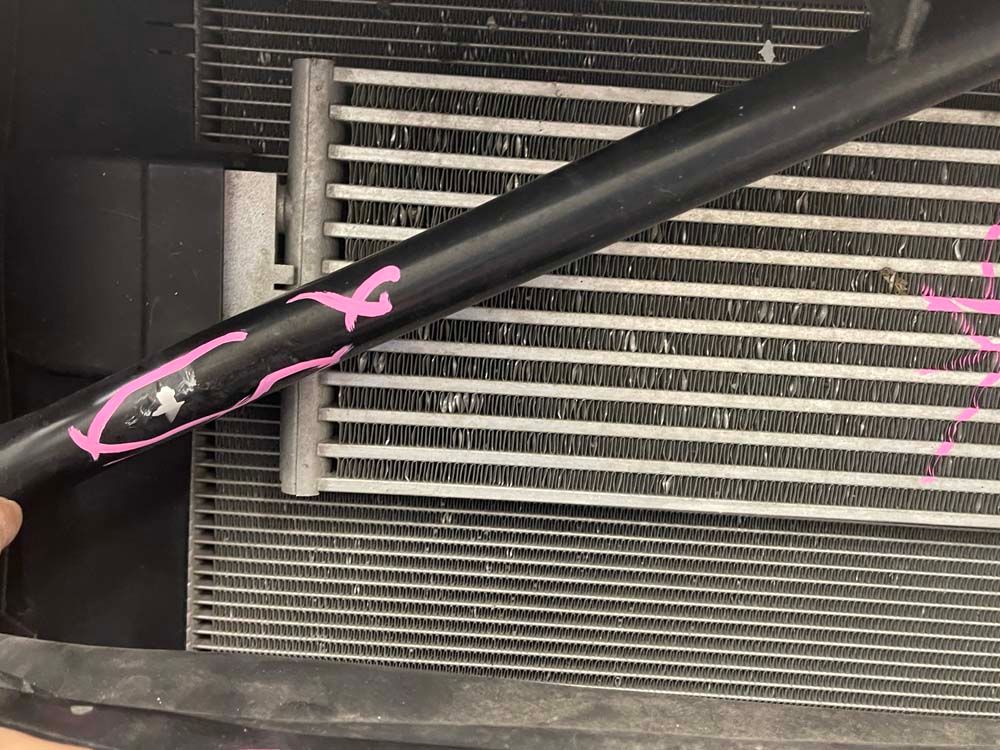 A person is holding a black pipe in front of a radiator.