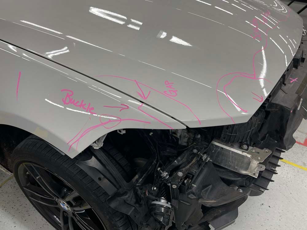 A close up of a damaged car with a pink marker drawing on it.