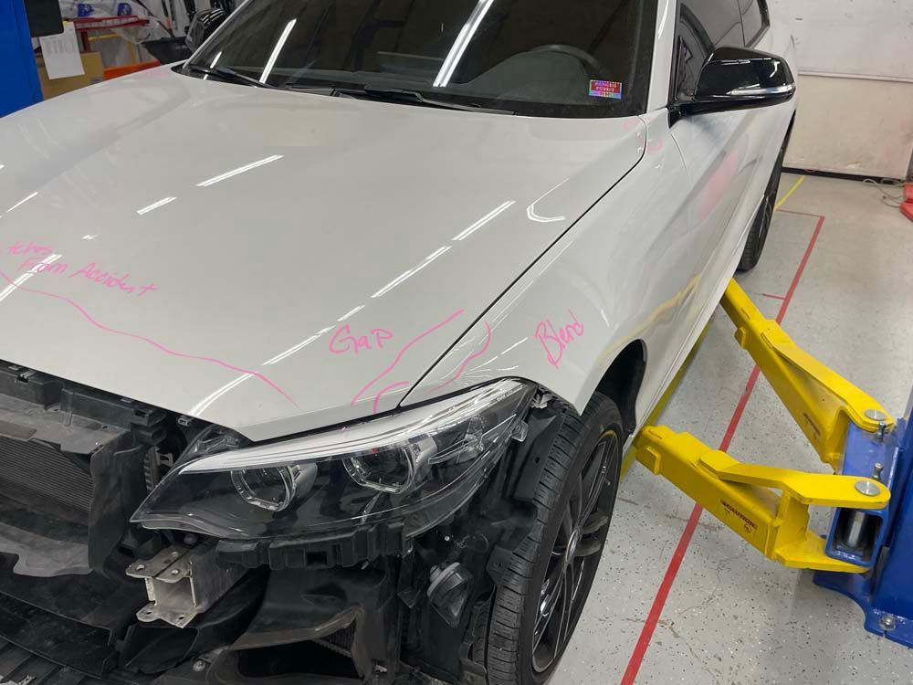 A white car is sitting on a lift in a garage.