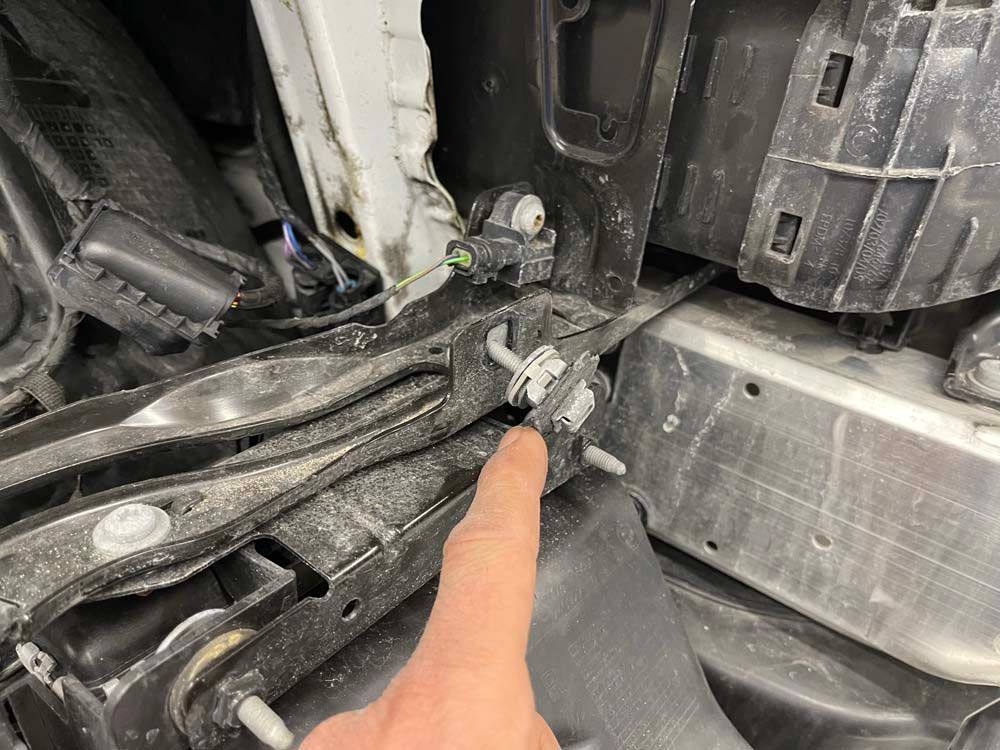 A person is pointing at a screw on the side of a car.