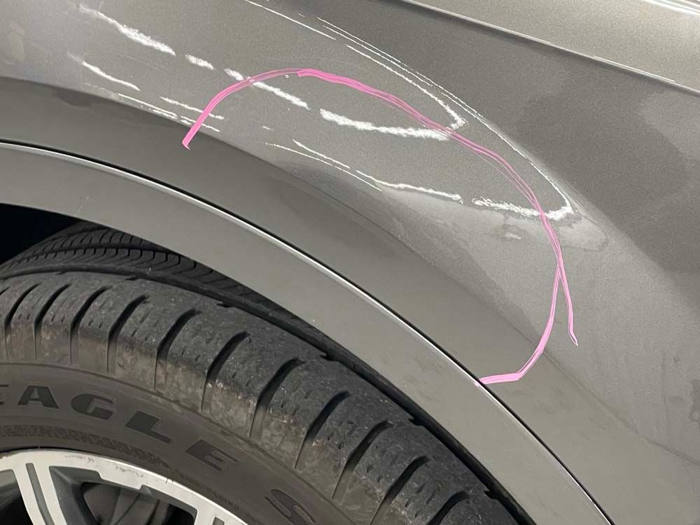 A close up of a car fender with a pink circle drawn on it.