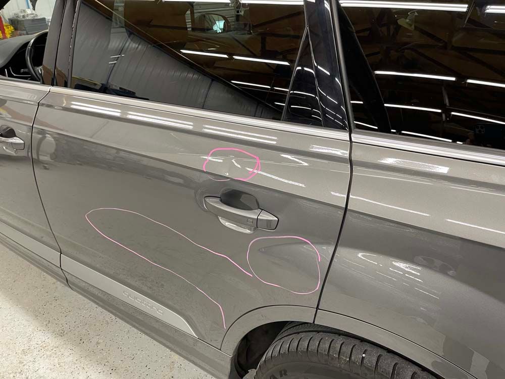 A close up of a gray car with a red circle on the door.