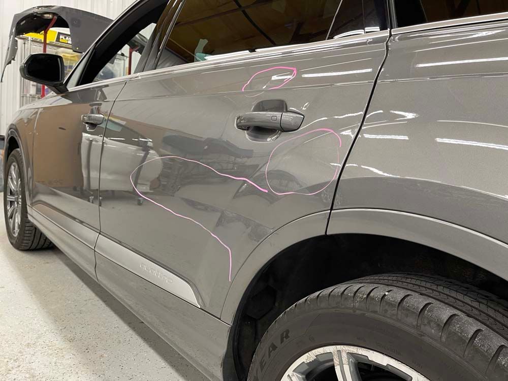 A gray car is parked in a garage with the door open.