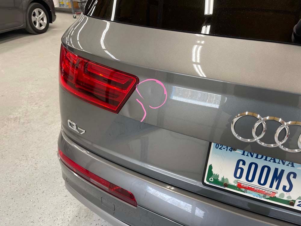 Gray Audi Q7 rear with Indiana license plate; pink circles highlight surface scratches.