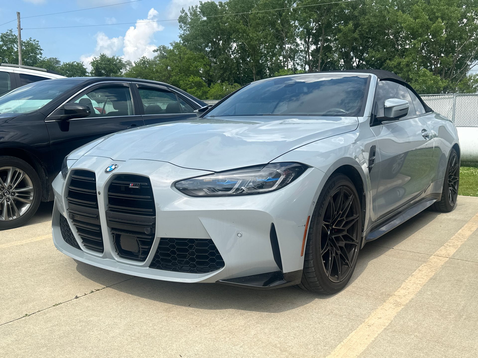 Gray BMW M4 convertible parked outside on a sunny day. Black wheels, grills, and trim.